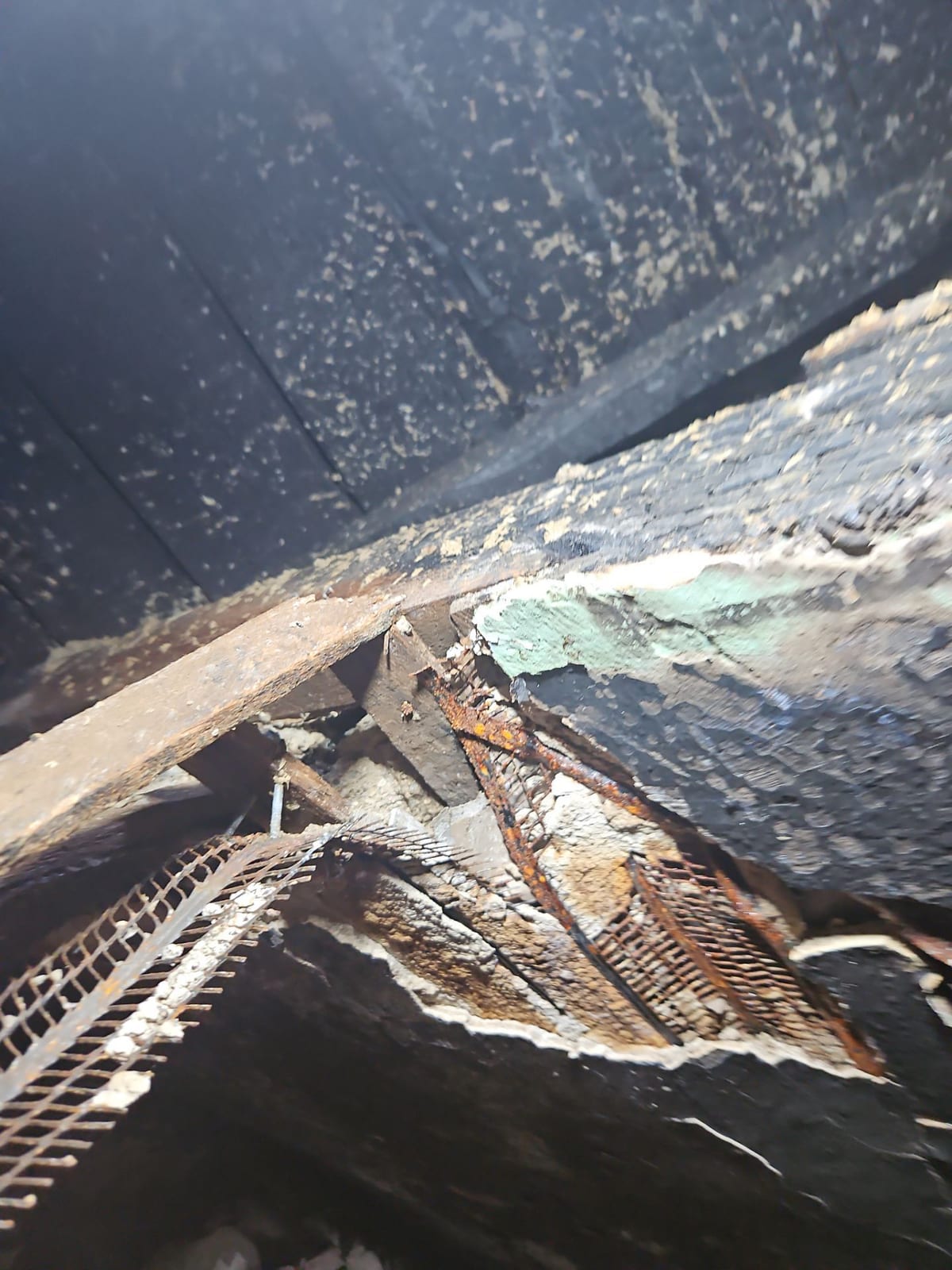 Ceiling collapse with charred, hanging lath.
