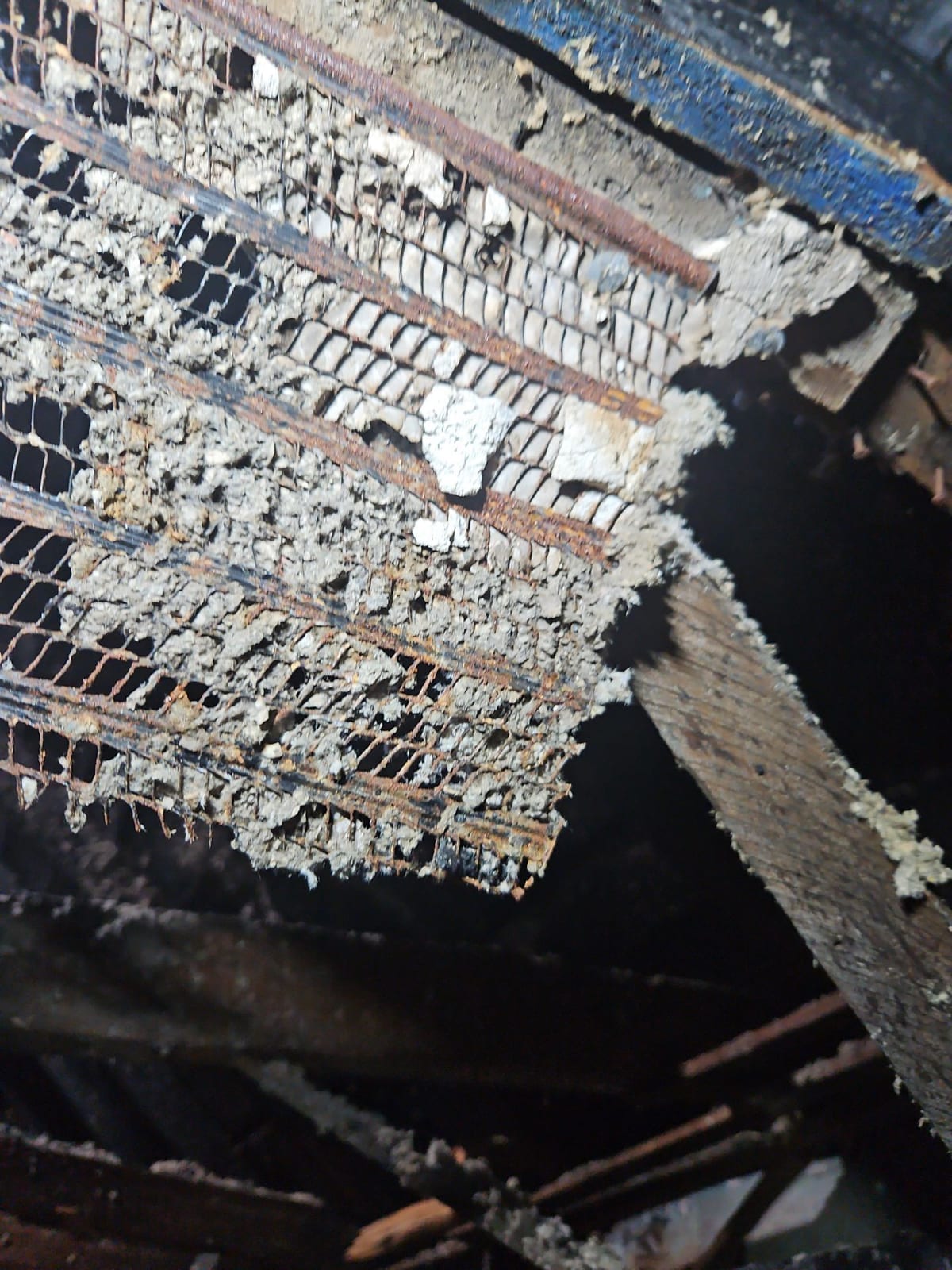 Charred ceiling joists and burned debris above the living space.