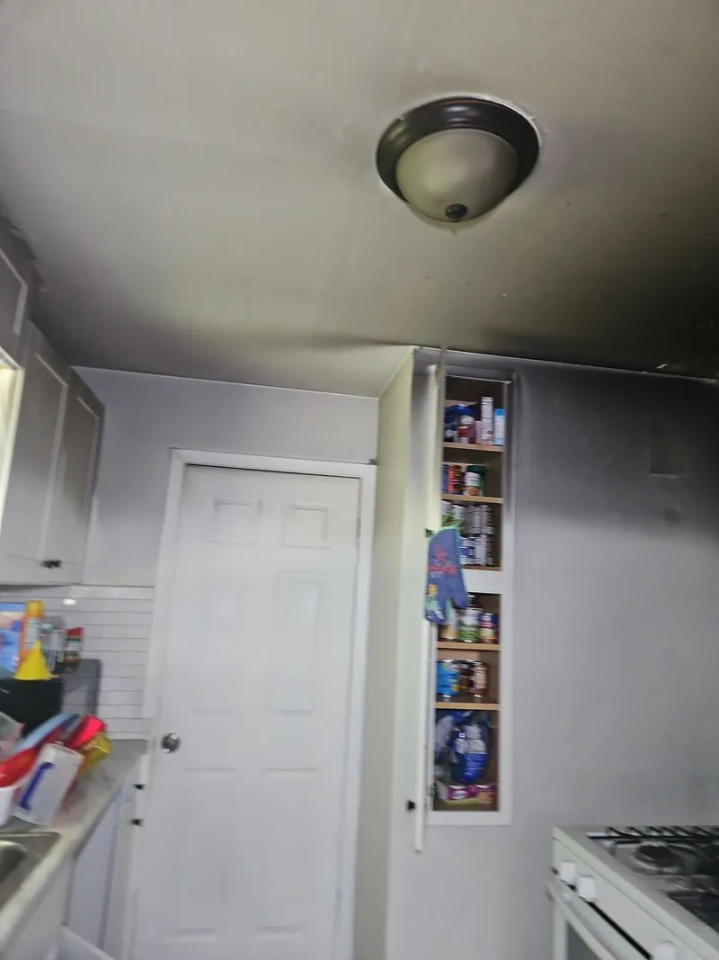 Soot plume rising up the wall and across the kitchen ceiling — the fire was contained, but the smoke wasn't.