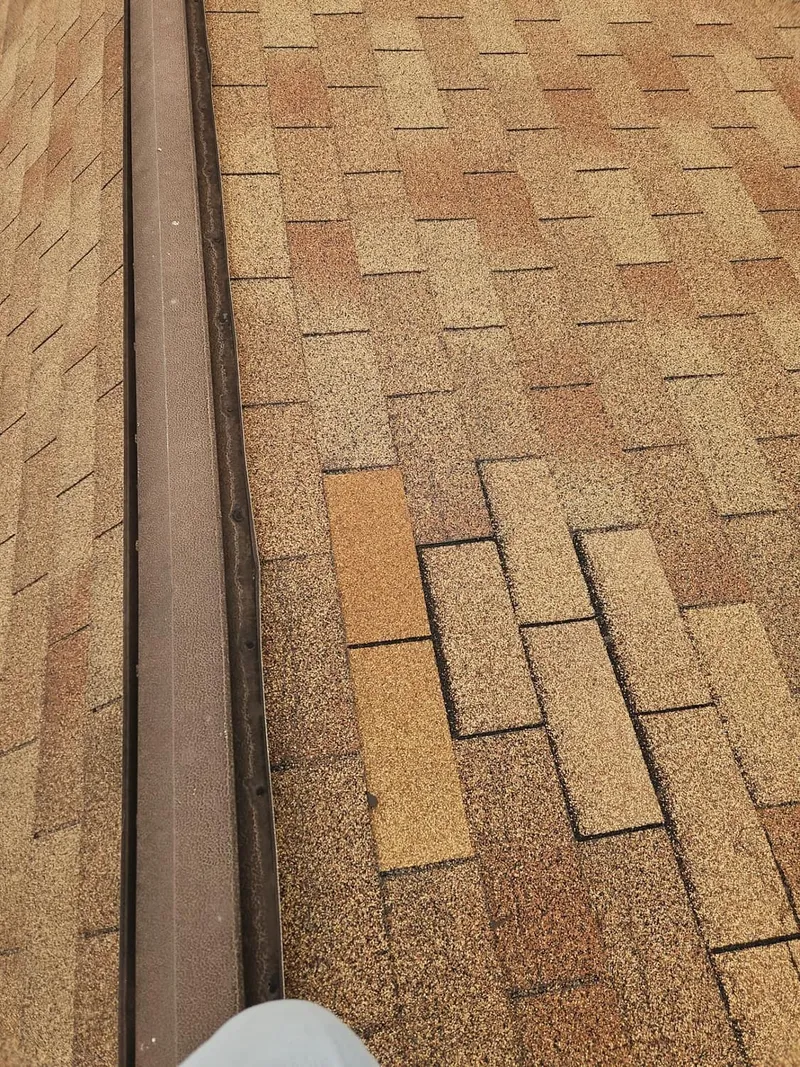 Lifted and curled shingle tabs along the edge, loosened by high winds.