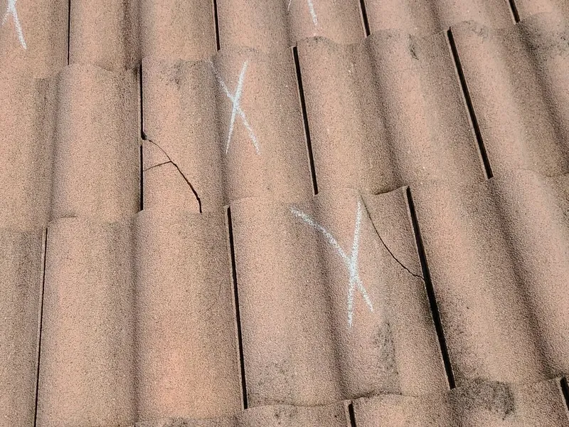 A cracked barrel tile marked in the field — impact damage insurers write off as 'wear.'