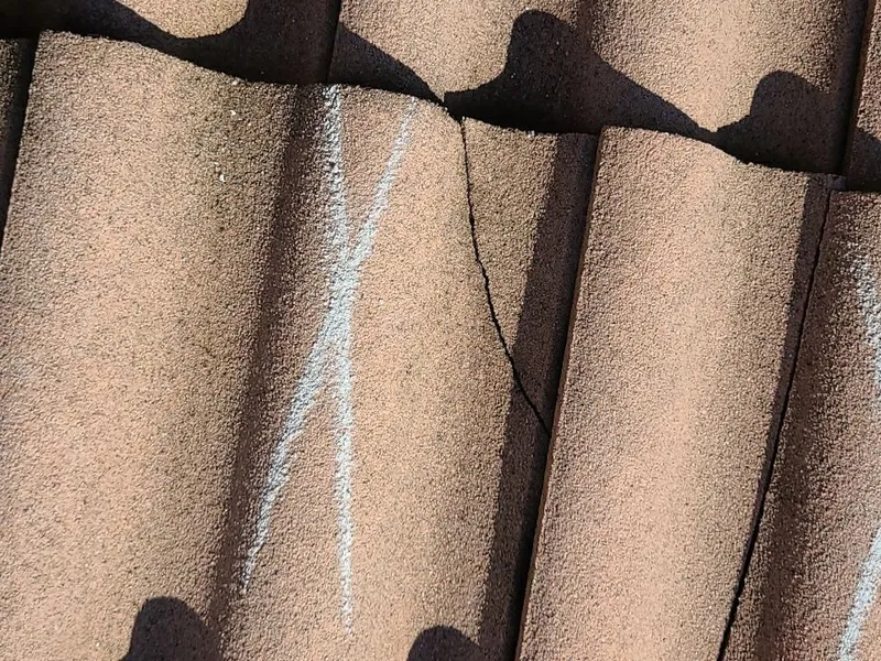 The crack runs the full length of the tile — once a tile is compromised, water reaches the underlayment.