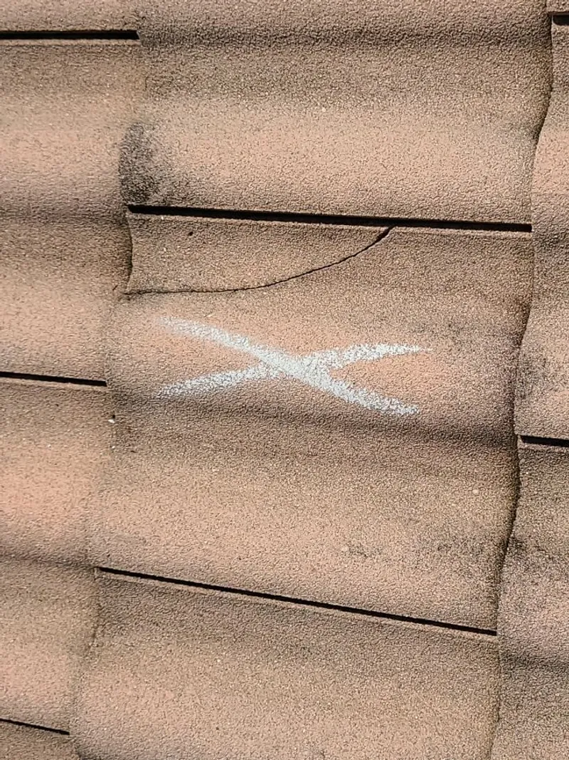 A fractured concrete tile, marked for the scope — one of dozens documented across the roof.