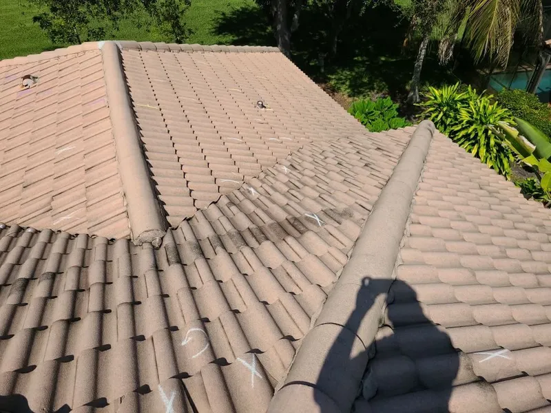 Chalk-marked storm damage across every slope — a cracked-tile pattern that spans the whole roof, not one corner.