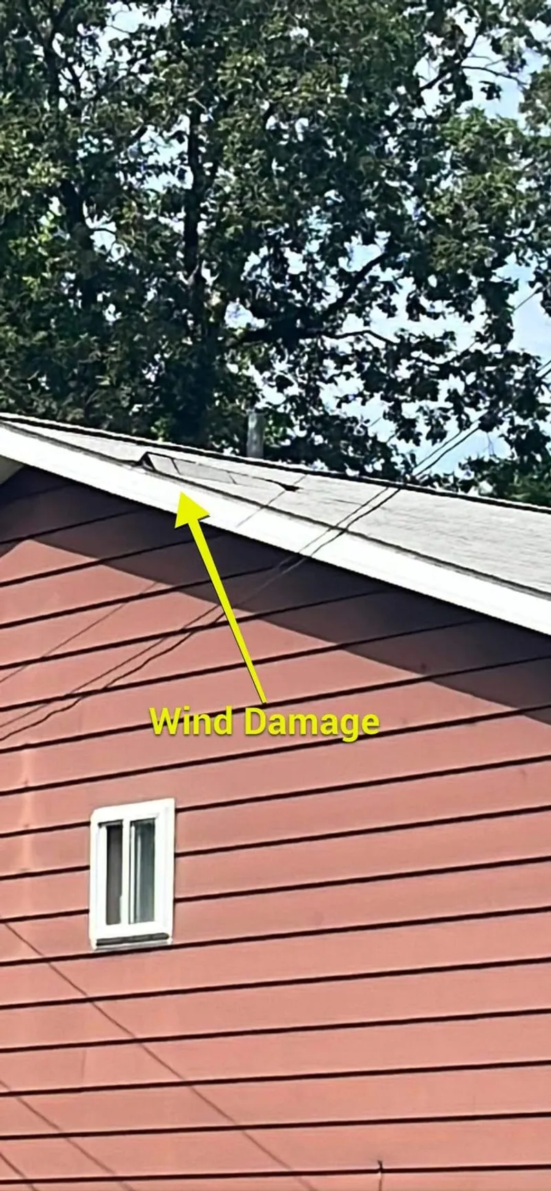 Field-marked damage at the gable end — the wind-exposed face that takes the brunt of a storm.